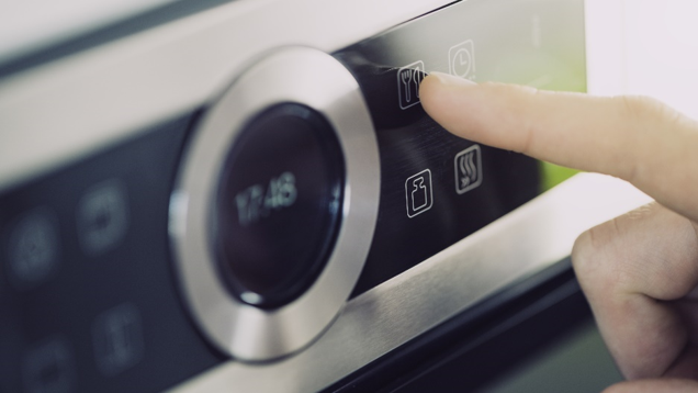 A finger pressing a button on a microwave